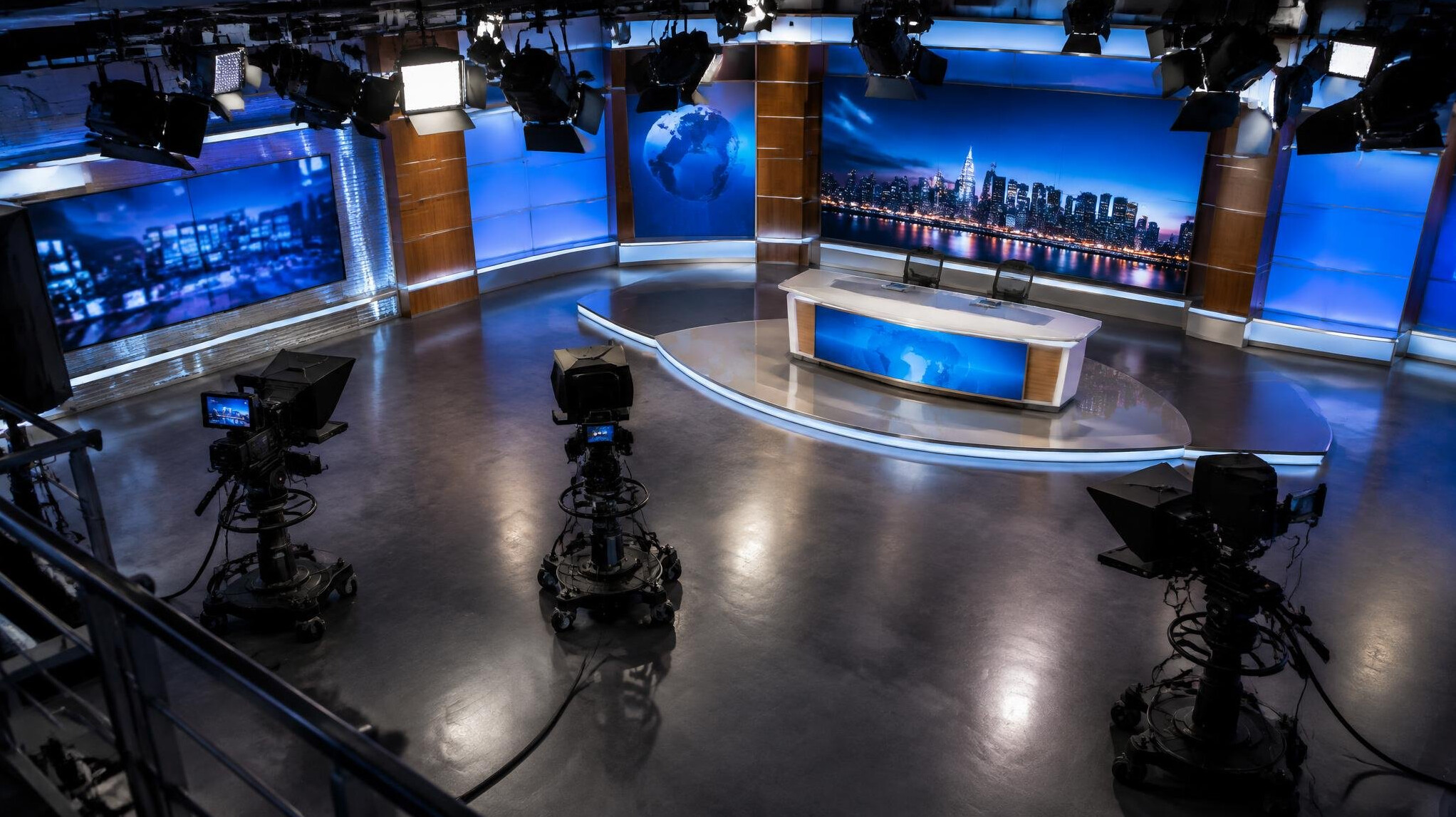 Wide view of an empty television studio set with cameras and lighting rigs