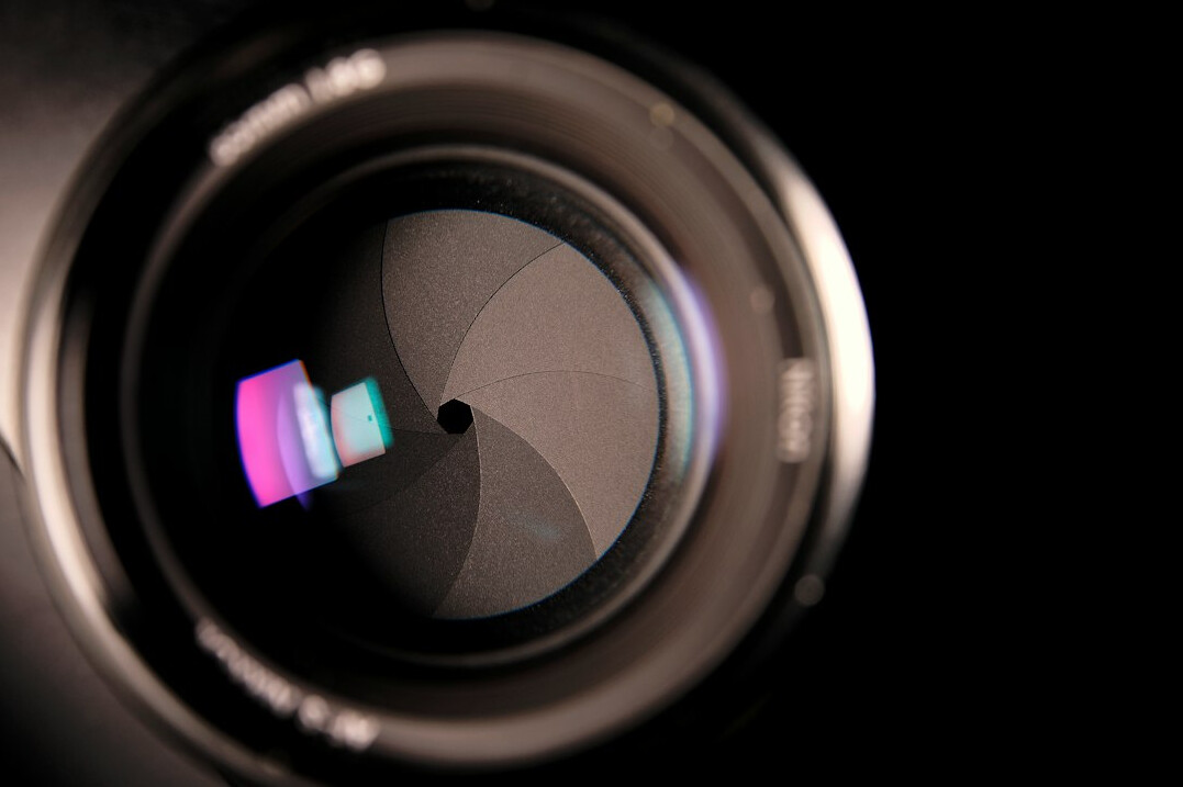 Close-up of a broadcast camera lens with studio reflections